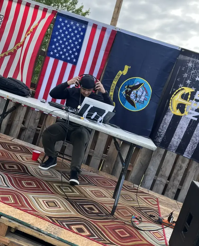 ColdOnes Events founder DJing at an outdoor event with American and Navy flags